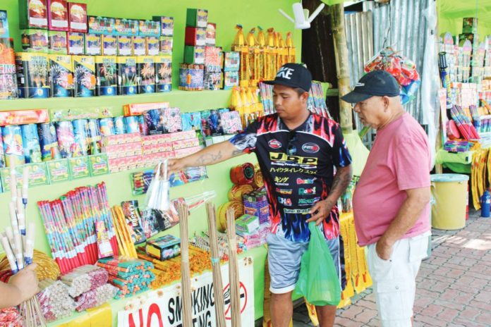 A firecracker vendor attends to a customer at his stall on Circumferential Road 1, Barangay Buhang, Jaro, Iloilo City. This area, one of the city’s three authorized locations for firecracker and pyrotechnic sales, draws a diverse crowd of locals and visitors, all eager to partake in the festive spirit with their purchases. AJ PALCULLO/PN