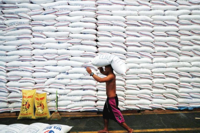 A worker carries a sack of rice on his head inside a government rice warehouse National Food Authority in Quezon City. REUTERS/ERIK DE CASTRO/FILES