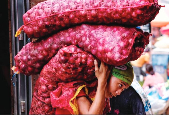 A worker unloads bags of red onions inside a storage area in Divisoria market in Manila in this file photo. The Department of Agriculture says imported fresh red and yellow onions will be arriving in the country on or before Dec. 31, 2023. GEORGE CALVELO, ABS-CBN NEWS/FILE PHOTO