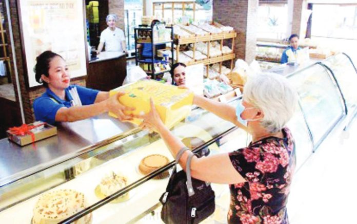 A customer claims her order from a bakery in Sampaloc, Manila in this file photo. The Asosasyon ng Panaderong Pilipino's leadership on Thursday, Dec. 14, said only select flour-based items may see price movements this holiday season. PNA PHOTO BY ROBERT OSWALD P. ALFILER