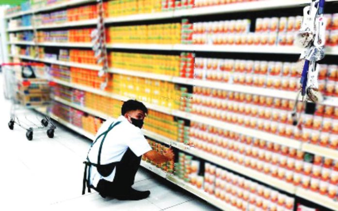 A worker arranges canned goods on the shelves in a grocery store in Quezon City in this undated photo. The Philippine Amalgamated Supermarkets Association on Tuesday, Dec. 5, said suppliers of basic commodities have not made significant adjustments to the prices of their goods. PNA PHOTO BY BEN BRIONES