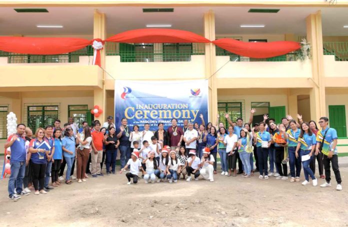 PAGCOR officers and Pura local officials pose with teachers and students of Nilasin 1st Elementary School in front of the new building.