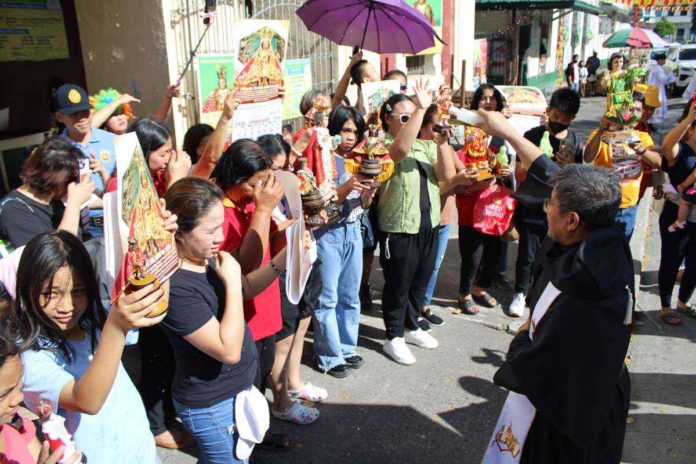 Devotees carry Sto. Niño images of varying sizes and have them blessed during yesterday’s religious motorcade around Iloilo City. AJ PALCULLO/PN