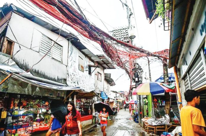 Electrical cables crisscross one another as electric meters hang on posts in Barangay Old Capitol, Quezon City on July 11, 2023. MARIA TAN/ABS-CBN NEWS PHOTO