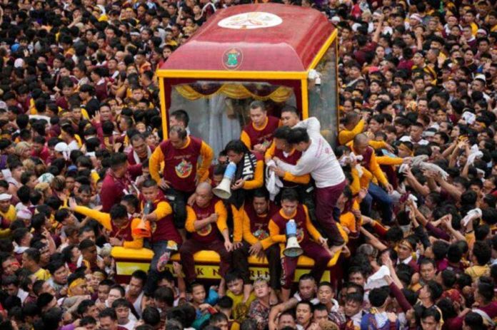 Devotees react as they try to block others from climbing on the glass-covered cart carrying Black Nazarene. AP