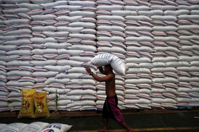 A worker carries on his head a sack of rice inside a government rice warehouse National Food Authority in Quezon City. The Department of Agriculture says President Ferdinand Marcos Jr. will seriously think about a proposal that would give rice – instead of cash – to beneficiaries of the Pantawid Pamilyang Pilipino Program). REUTERS/ERIK DE CASTRO/FILES