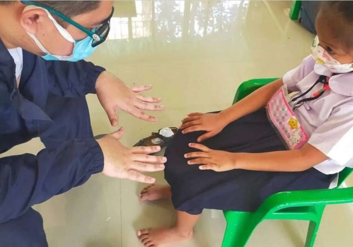 A health worker examines the hand of a girl in Batangas to check on possible signs of hand-foot-and-mouth disease (HFMD), a mild, contagious viral infection common in young children. PHOTO COURTESY OF RAPPLER