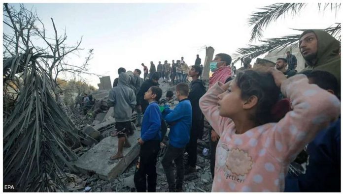 Palestinians watch as people search for bodies and survivors among the rubble following Israeli airstrikes on the west of Al Nusairat refugee camp, southern Gaza Strip. EPA