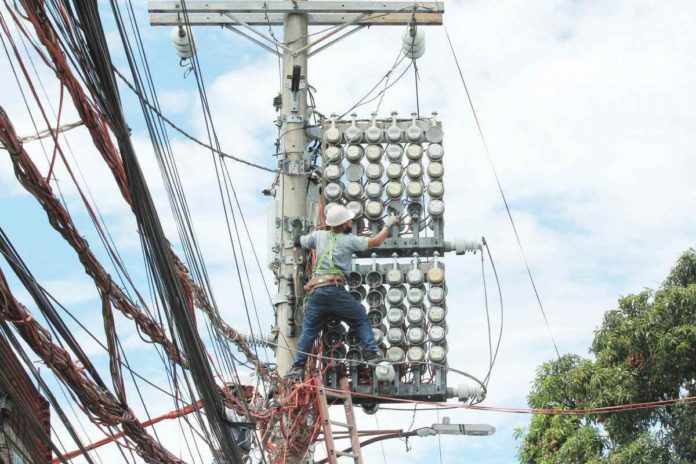 One of the Manila Electric Co. linemen inspects the power meters on a concrete post along Kaliraya Street in Quezon City. PNA PHOTO BY JESS M. ESCAROS JR.