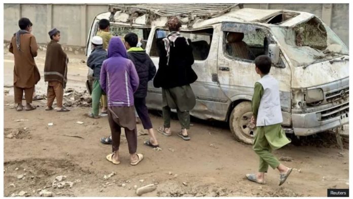 People look at a flood-wrecked vehicle in Baghlan province, Afghanistan. REUTERS