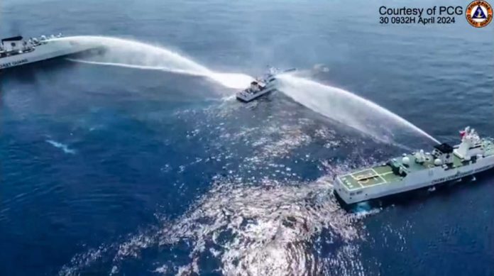 This frame grab from handout video footage taken and released on April 30, 2024, by the Philippine Coast Guard (PCG) shows the Philippine Coast Guard ship BRP Bagacay (C) being hit by a water cannon from Chinese Coast Guard vessels near the Chinese-controlled Scarborough shoal in disputed waters of the South China Sea. The Philippines said the China Coast Guard fired a water cannon on April 30 at two of its vessels, causing damage to one of them, during a patrol near a reef off the Southeast Asian country. PHOTO BY HANDOUT / PHILIPPINE COAST GUARD / AFP