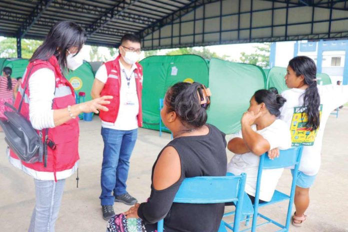 Arwin O. Razo (standing, 2nd from left), assistant regional director for operations of the Department of Social Welfare and Development Region 6, looks into the situation of evacuees in La Castellana evacuation sites in Negros Occidental. DSWD-6 PHOTO