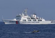 A China Coast Guard ship monitors a Philippine fisherman aboard his wooden boat during the distribution of fuel and food to fishers by the civilian-led mission Atin Ito (This Is Ours) Coalition, in the disputed South China Sea on May 16, 2024. AFP