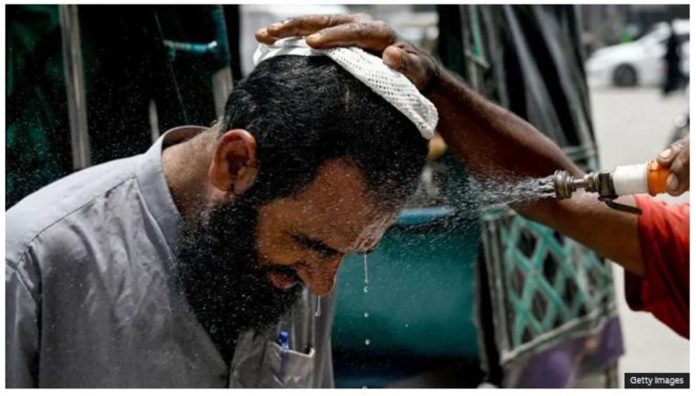 In Karachi, a volunteer sprays water on a bypasser’s face to cool off during a heat wave. GETTY IMAGES