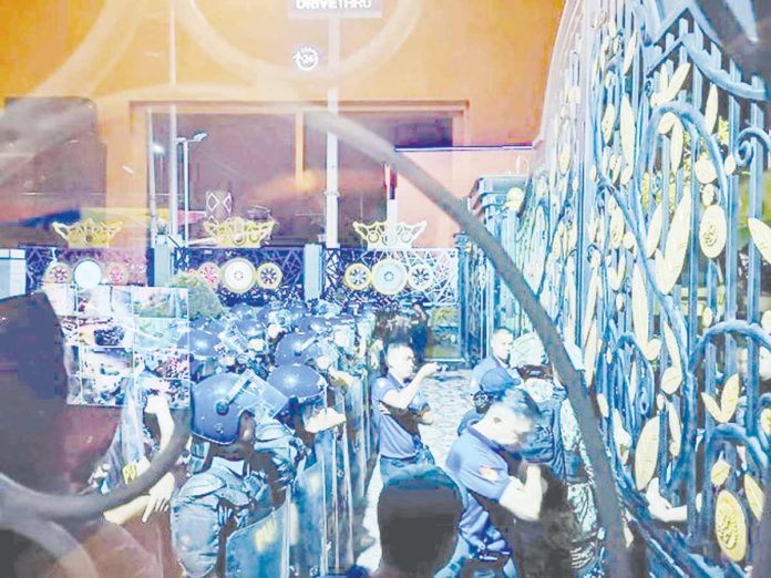 Policemen in anti-riot gear move in closer to the gate of rthe Kingdom of Jesus Christ compound in Davao City where Pastor Apollo Quiboloy is supposedly hiding. PHOTO FROM X