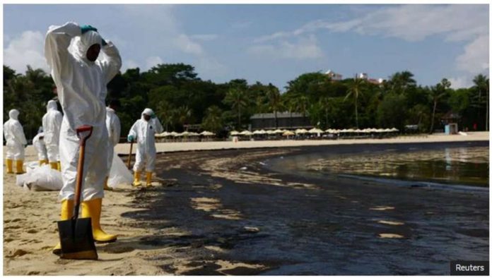 Workers in full body suits clean up the oil spill at the tourist attraction Tanjong Beach. REUTERS