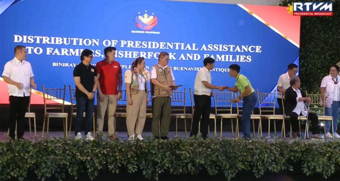 A farmer from Antique receives financial aid from President Ferdinand “Bongbong” Marcos Jr. during a ceremonial turnover on June 27, at the Binirayan Sports Complex in San Jose de Buenavista, Antique. PCO