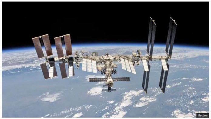 The International Space Station photographed by an astronaut with Earth in the background. It has a long reflective surface with lots of solar panels sticking out from it. REUTERS