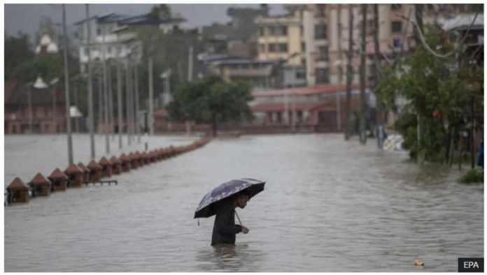 A person wades through a flooded street caused by the swollen Bagmati River after torrential rains in Kathmandu, Nepal on July 6, 2024. Streets in the Nepalese capital Kathmandu were flooded over the weekend from overflowing rivers. EPA