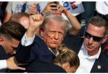 Despite his wounded ear, former US President Donald Trump – while being quickly covered by his Secret Service – still managed to pump his fist in the air and shout, “Fight! Fight! Fight!” Streaks of blood can be seen on his face. BBC