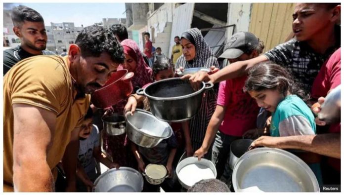 Palestinians wait to receive food at a charity kitchen in Khan Younis, in the southern Gaza Strip. REUTERS