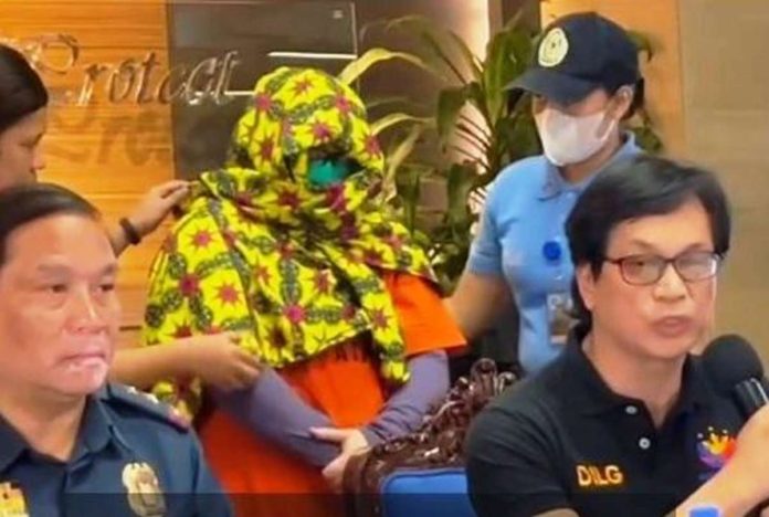 Interior Secretary Benjamin Abalos Jr. (right) presents during a press conference a masked Paulene Canada (center), a co-accused of Kingdom of Jesus Christ founder Pastor Apollo Quiboloy. She was arrested in Davao City.