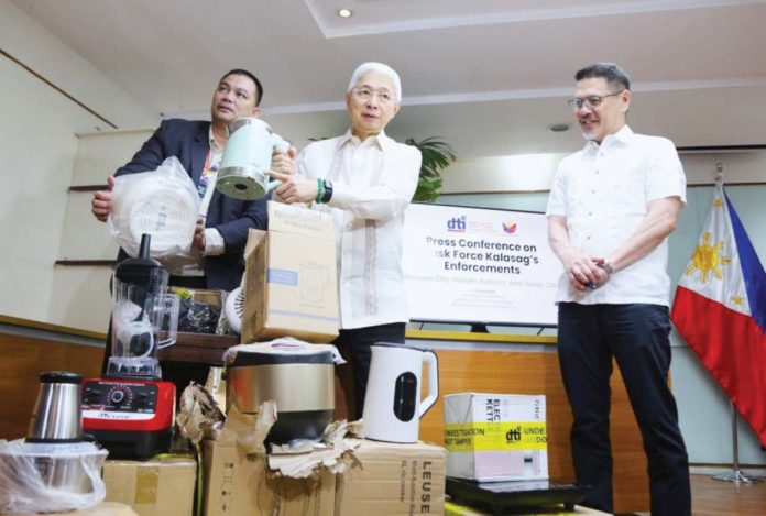 Department of Trade and Industry Secretary Fred Pascual (center) says that the agency’s Task Force Kalasag’s three separate raids across Valenzuela City, Bulacan and Cavite brought about P25.4 million in uncertified home appliances and consumer goods. DTI PHOTO