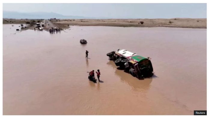 People stand next to an overturned vehicle in flood waters in Yemen. REUTERS