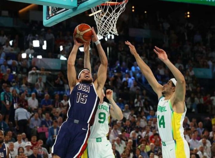 Devin Booker of the US team attacks two Brazilian defenders and makes a layup. REUTERS