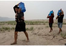 People carry drinking water along a sandbank of Madeira River in Paraizinho Community, in Humaita, Amazonas state, northern Brazil. Rivers are dying up. GETTY IMAGES