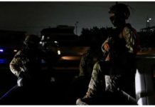 Two people in military fatigues sit in the bed of a truck in a street enveloped in darkness in Ecuador due to a blackout. REUTERS