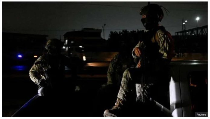 Two people in military fatigues sit in the bed of a truck in a street enveloped in darkness in Ecuador due to a blackout. REUTERS