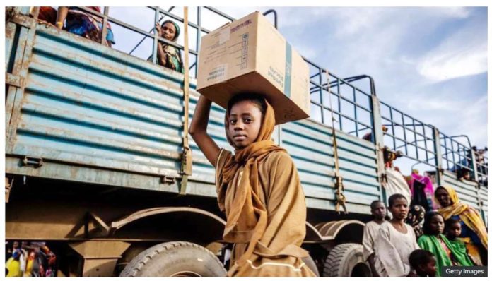 A Sudanese girl who have fled the war with her family carries a box of belongings after arriving at a transit center for refugees in Renk in South Sudan. GETTY IMAGES