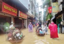 People wade through a flooded street following the impact of Typhoon Yagi, in Hanoi, Vietnam. Residents have been using boats to navigate their neighborhoods as flood waters reached a meter high. REUTERS