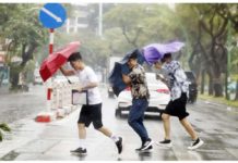 People hold umbrellas as they cross a street under the rain in Hanoi, Vietnam. EPA