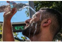 A man pours water over his head to cool down. Little progress has been made in limiting emissions of greenhouse gases that are driving up temperatures. GETTY IMAGES