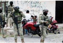 Four Mexican army soldiers stand guard. They are armed with assault rifles, as well as wearing full military gear and facemask. GETTY IMAGES