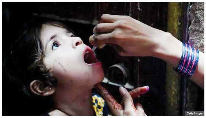 A health worker administers polio vaccine drops to a young girl during a polio vaccination campaign in Karachi, Pakistan. Pakistani officials are preparing to launch a nationwide vaccination campaign for children under five. GETTY IMAGES