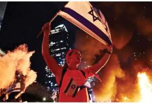 A person holds an Israeli flag as people demonstrate after Israeli Prime Minister Benjamin Netanyahu sacked his defense minister, Yoav Gallant, citing lack of trust, in Tel Aviv, Israel. REUTERS