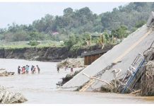 People cross a river next to a bridge that collapsed after the river overflew due to heavy rains brought about by Severe Tropical Storm Kristine in Laurel, Batangas province, south of Manila on October 25, 2024. Photo by Ted ALJIBE / AFP