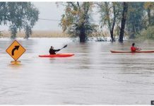 Kayakers row passed a street sign on a flooded road in California. GETTY IMAGES