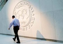 A man walks past the International Monetary Fund logo at its headquarters in Washington, U.S. REUTERS/YURI GRIPAS/FILE PHOTO