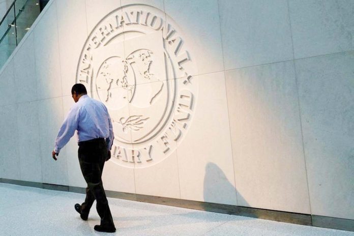 A man walks past the International Monetary Fund logo at its headquarters in Washington, U.S. REUTERS/YURI GRIPAS/FILE PHOTO