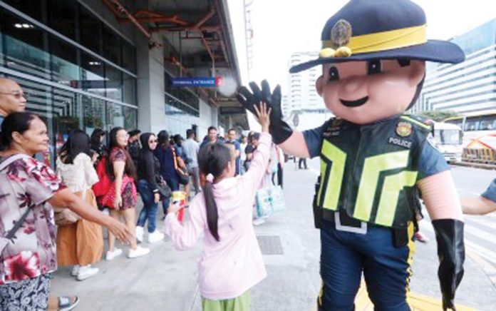 A mascot of the Philippine National Police greets a child with a high five outside the Parañaque Integrated Terminal Exchange on Oct. 31, 2024. The Land Transportation Franchising and Regulatory Board on Thursday, Dec. 19, 2024, said it issued 956 special permits to public utility vehicles (PUV), increasing the number of available PUVs such as buses in routes that will be particularly busy during the holiday season. PNA PHOTO BY AVITO DALAN