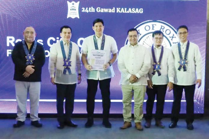 Mayor Ronnie Dadivas (third from left) and City Disaster Risk Reduction and Management head Pong Saneo (fourth from left) receive the “Beyond Compliant” seal of the Gawad Kalasag for Roxas City during the awarding ceremony in Iloilo City on Dec. 11, 2024. MAYOR RONNIE DADIVAS FACEBOOK PAGE PHOTO