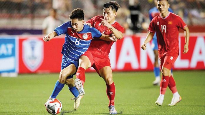 Philippine men’s football team’s Sandro Reyes tries to control the ball while being defended by a Vietnam player. GETTY IMAGES