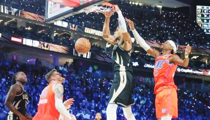 Giannis Antetokounmpo of Milwaukee Bucks dunks ahead of Shai Gilgeous-Alexander of Oklahoma City Thunder. GETTY IMAGES