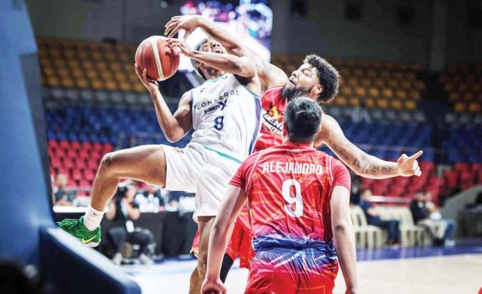 Converge FiberXers’ Deschon Winston is clobbered by the defense of Phoenix Fuel Masters’ Donovan Smith as he goes for an inside hit. PBA PHOTO