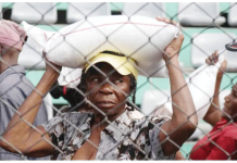 A woman receives food during a solidarity day organized by the Haitian government in Port-au-Prince, Haiti. She carries a sack on her head. Many Haitians have been forced to flee due to gang violence. EPA