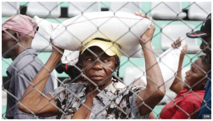 A woman receives food during a solidarity day organized by the Haitian government in Port-au-Prince, Haiti. She carries a sack on her head. Many Haitians have been forced to flee due to gang violence. EPA